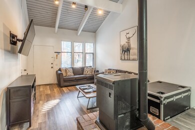 Living room featuring light wood-style floors, wooden ceiling, and a wood stove