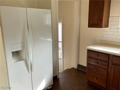 Kitchen featuring decorative backsplash, dark tile patterned flooring, and white fridge with ice dispenser