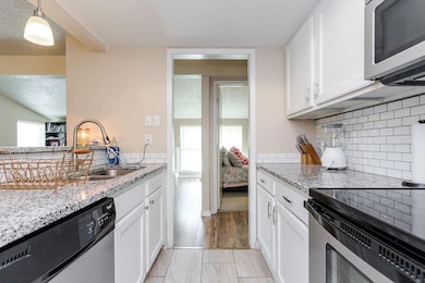 Kitchen with white cabinets, light stone counters,