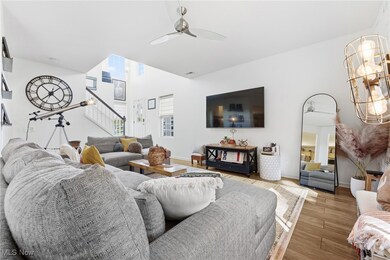 Living room with wood finished floors, a ceiling fan, and stairway