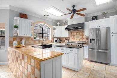 Kitchen featuring white cabinetry, sink, wall chim