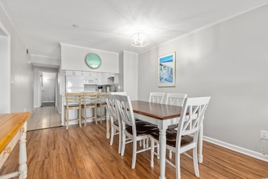 Dining room featuring light wood finished floors, ornamental molding, a textured ceiling, and a chandelier