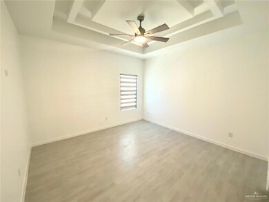 Empty room with a tray ceiling, wood finished floors, and ceiling fan