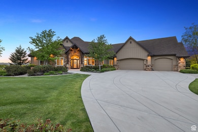 View of front facade featuring stone siding, a yard, a garage, and concrete driveway