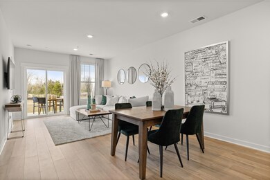 Great room and dining space are filled with natural light from the large rear window and sliding glass door. Photo of decorated model home of this floorplan, not actual home listed.