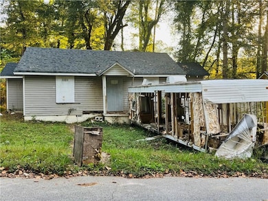 View of front of home with a shingled roof and view of scattered trees