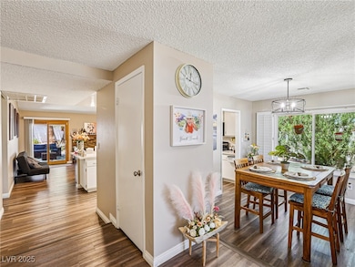 Dining room with wood finished floors, a textured ceiling, and a chandelier