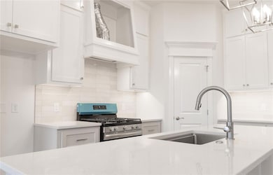 Kitchen with tasteful backsplash, light stone countertops, stainless steel gas range, and custom exhaust hood