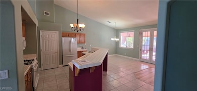 Kitchen featuring tile counters, white appliances, hanging light fixtures, a chandelier, and light tile patterned flooring