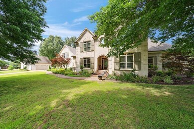 Traditional-style home with a front lawn, stucco siding, a garage, and an outbuilding