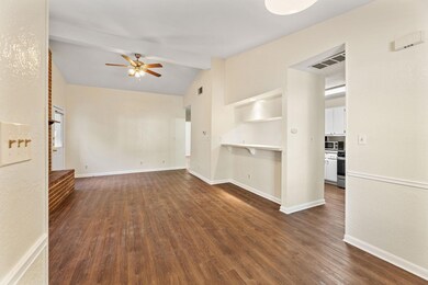 Unfurnished living room featuring dark wood-style flooring and a ceiling fan
