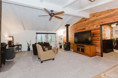 Open concept with ceiling fan, wood stove and vaulted ceilings.