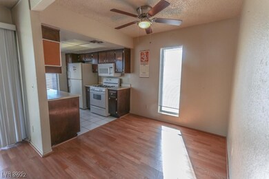 Kitchen with white appliances, a textured ceiling, light countertops, light wood-style floors, and ceiling fan