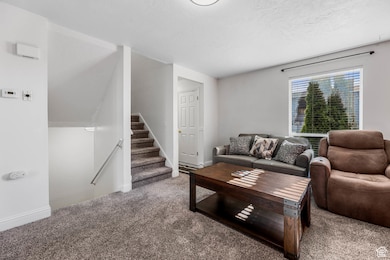 Carpeted living area featuring stairway and a textured ceiling