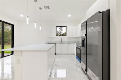 Kitchen with appliances with stainless steel finishes, modern cabinets, white cabinets, and recessed lighting