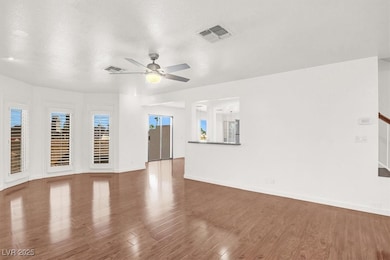 Unfurnished living room featuring a textured ceiling, wood finished floors, plenty of natural light, and a ceiling fan