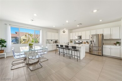 Kitchen with a breakfast bar area, appliances with stainless steel finishes, white cabinetry, and an island with sink