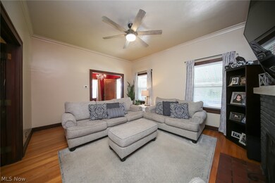Living room featuring a fireplace, ceiling fan, crown molding, and hardwood / wood-style flooring