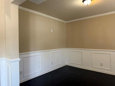 Unfurnished room featuring dark wood-type flooring, ornamental molding, and a wainscoted wall