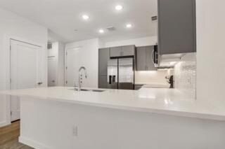 Kitchen featuring stainless steel fridge, gray ca