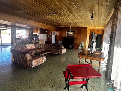 Living area with speckle patterned floor, wooden walls, and wooden ceiling
