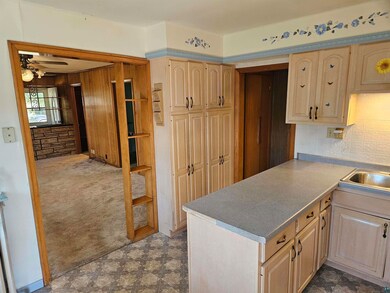 Kitchen with dark colored carpet, ceiling fan, lig