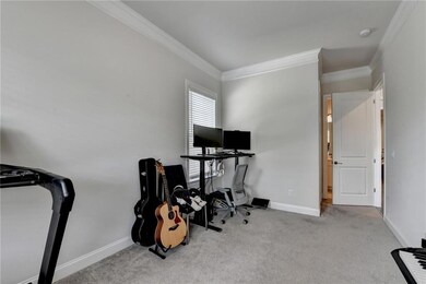 Carpeted office space featuring crown molding