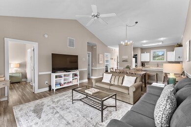 Living room featuring a chandelier, ceiling fan, wood finished floors, and high vaulted ceiling