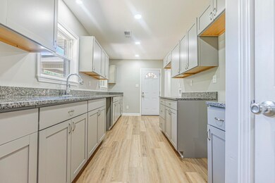 Kitchen featuring gray cabinetry, light stone coun