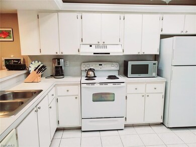 Kitchen with white appliances, white cabinetry, light countertops, and ventilation hood