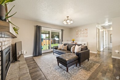 Living area featuring a brick fireplace, a textured ceiling, dark wood-style floors, and a chandelier