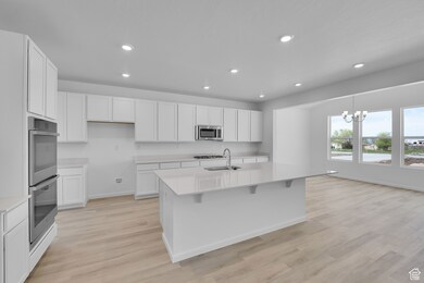 Kitchen featuring appliances with stainless steel finishes, light countertops, recessed lighting, white cabinetry, and light wood-style flooring