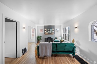 Living room featuring a brick fireplace, light wood-style floors, and arched walkways