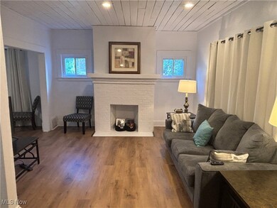 Living room featuring hardwood / wood-style floors, wood ceiling, and a brick fireplace