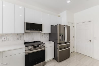 Kitchen featuring appliances with stainless steel finishes, white cabinetry, modern cabinets, and tasteful backsplash