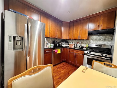 Kitchen with appliances with stainless steel finishes, dark wood-type flooring, and tasteful backsplash