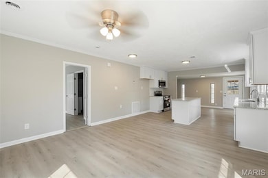 Unfurnished living room with crown molding, baseboards, a sink, light wood finished floors, and a ceiling fan