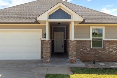 Property entrance with a garage, roof with shingles, brick siding, and driveway