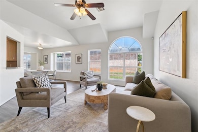 Living area with wood floors, vaulted ceiling, and a ceiling fan