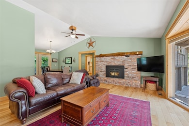 The living area with fireplace, lofted ceiling and ceiling fan