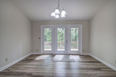 Doorway to outside with a chandelier and wood finished floors