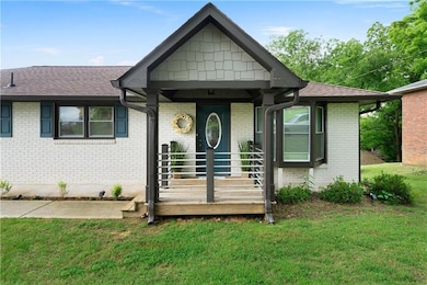 View of front facade featuring a front lawn, roof with shingles, and brick siding
