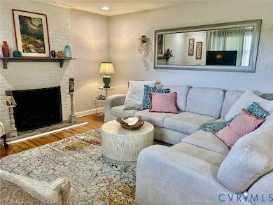 Living area featuring wood finished floors, a brick fireplace, and recessed lighting