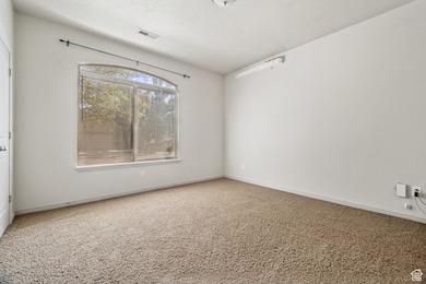 Carpeted spare room featuring baseboards