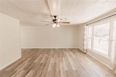 Spare room featuring light wood-style flooring, a textured ceiling, and ceiling fan