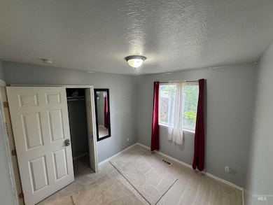 Unfurnished bedroom featuring light colored carpet, a textured ceiling, and a closet