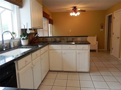 The kitchen has granite countertops, a tile backsplash, and clean, white cabinetry.