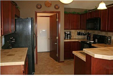 Kitchen has beautiful dark wood cabinets, tiled co