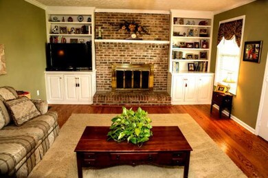 Relax by the Wood Burning Fireplace!  This Living Room features Custom Built-ins and an Entry to the Back Patio.