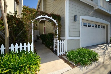 THROUGH A PLANTED ARBOR AND GARDEN PATH WITH CLASSIC PICKET FENCE.